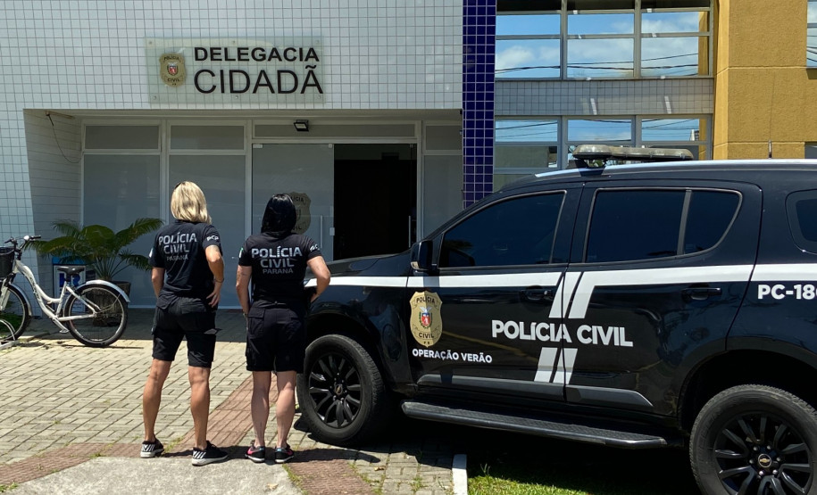 Duas policiais ao lado de viatura em frente à delegacia de matinhos