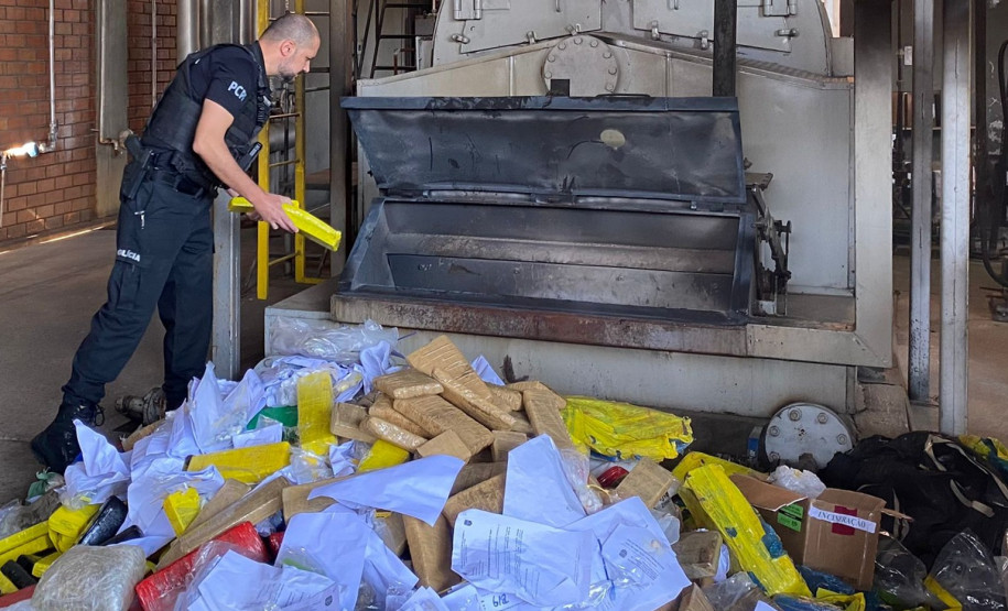 Policial civil jogando um dos tabletes de droga no incinerador
