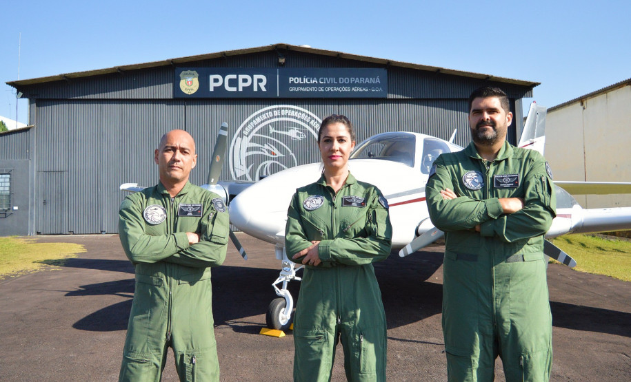 Pilotos posando para fotografia em frente a um avião