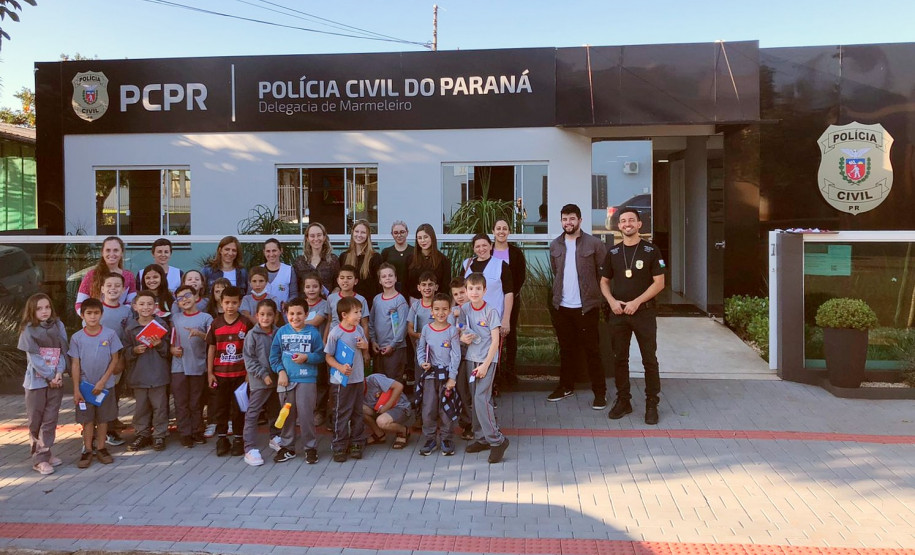 Policiais civis e alunos reunidos em frente à delegacia