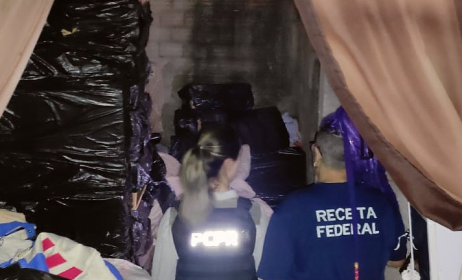 Policial civil e servidora da Receita Federal observam depósito com cigarros contrabandeados