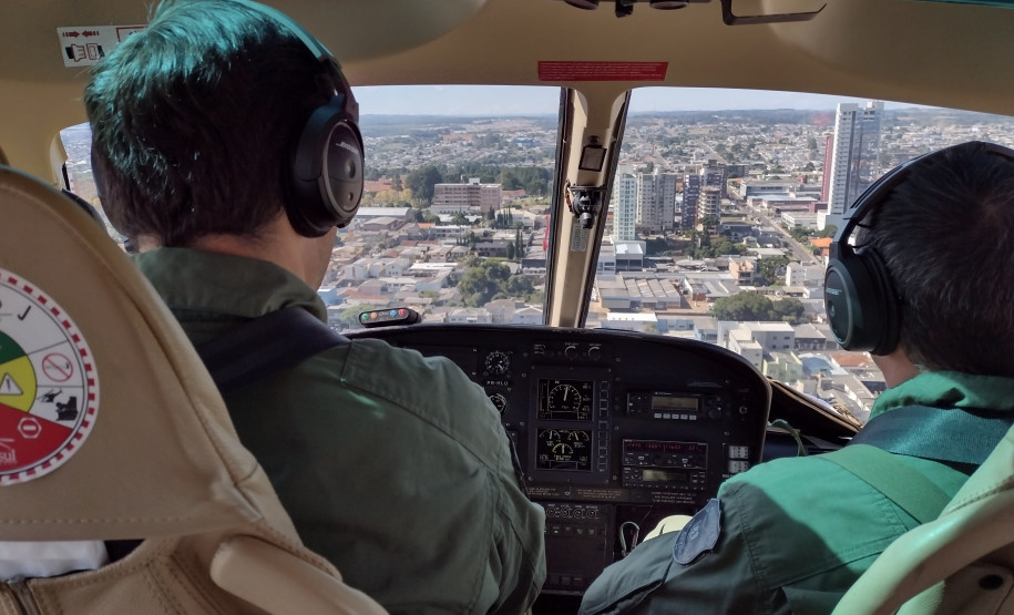 Pilotos em helicóptero sobrevoando a cidade