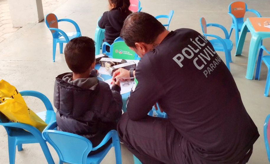 Policial civil acompanha criança em atividade lúdica