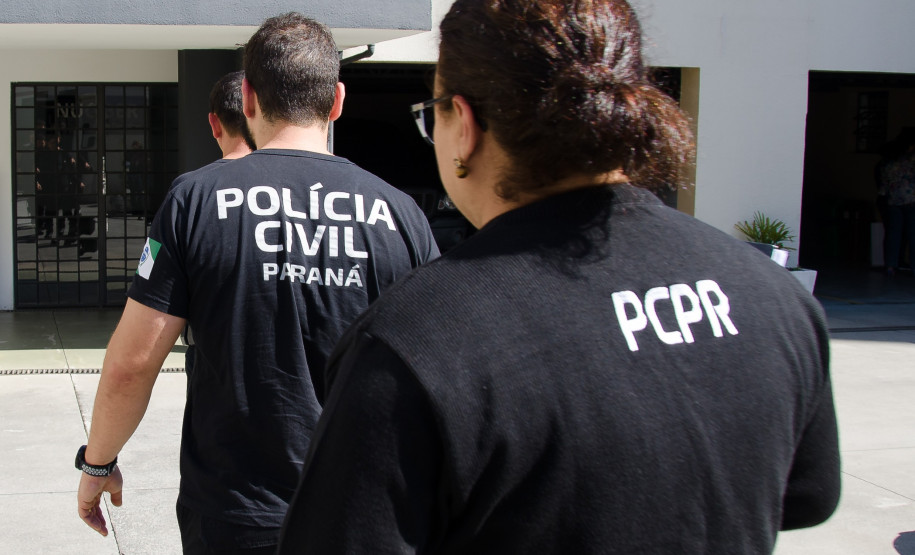 Três policiais civis entrando em delegacia