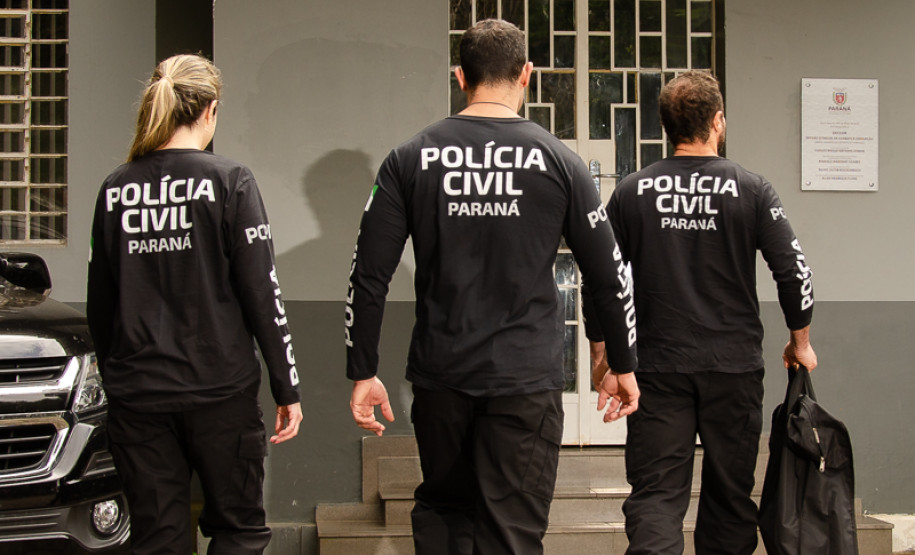 Três policiais civis em frente a delegacia