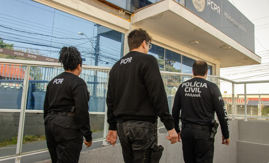 Três policiais civis em frente à delegacia