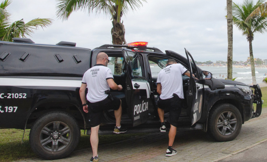 Dois policiais civis entrando em viatura