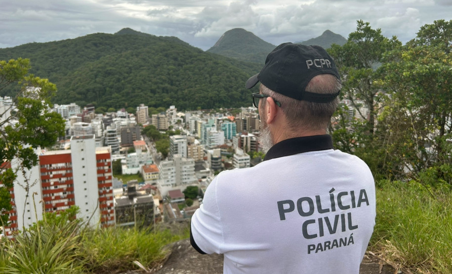 Policial civil observa cidade do alto de um morro