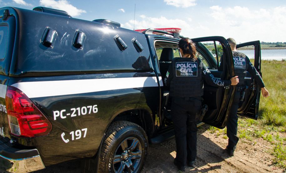 Dois policiais civis entrando em viatura