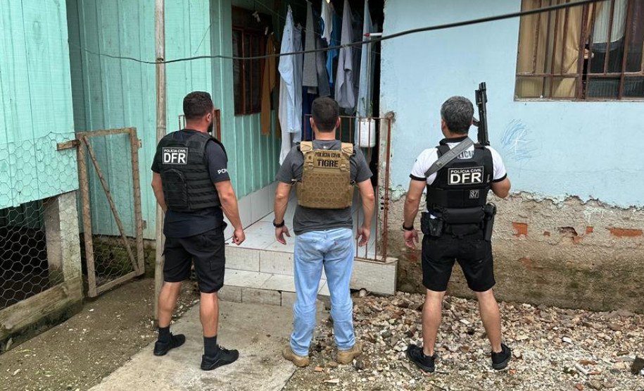 Três policiais em frente a residencia