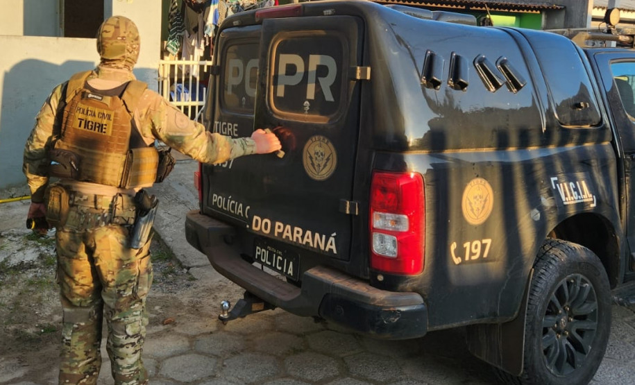 Policial civil ao lado de viatura