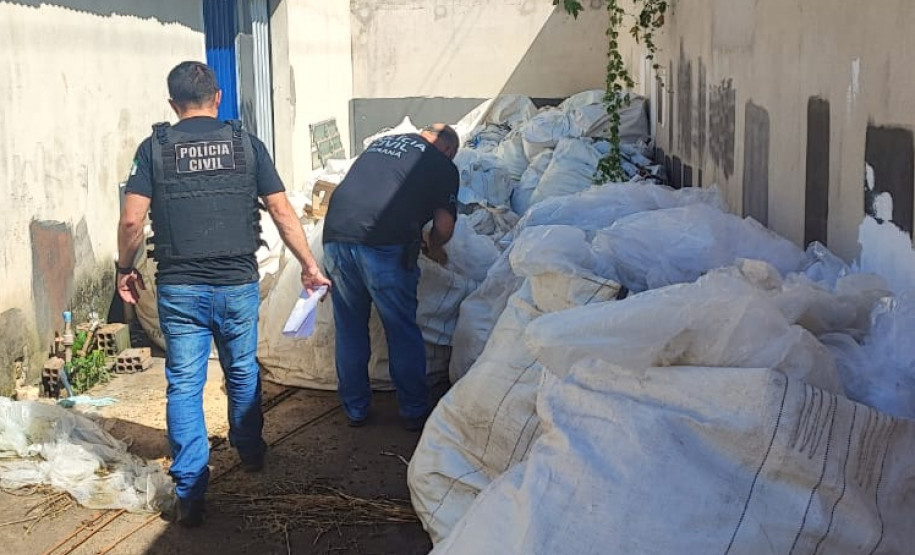 Dois policiais civis analisam sacos de fertilizante apreendidos