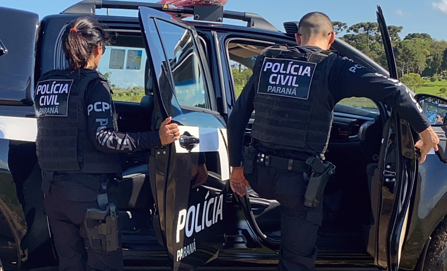 Dois policiais civis entrando em viatura