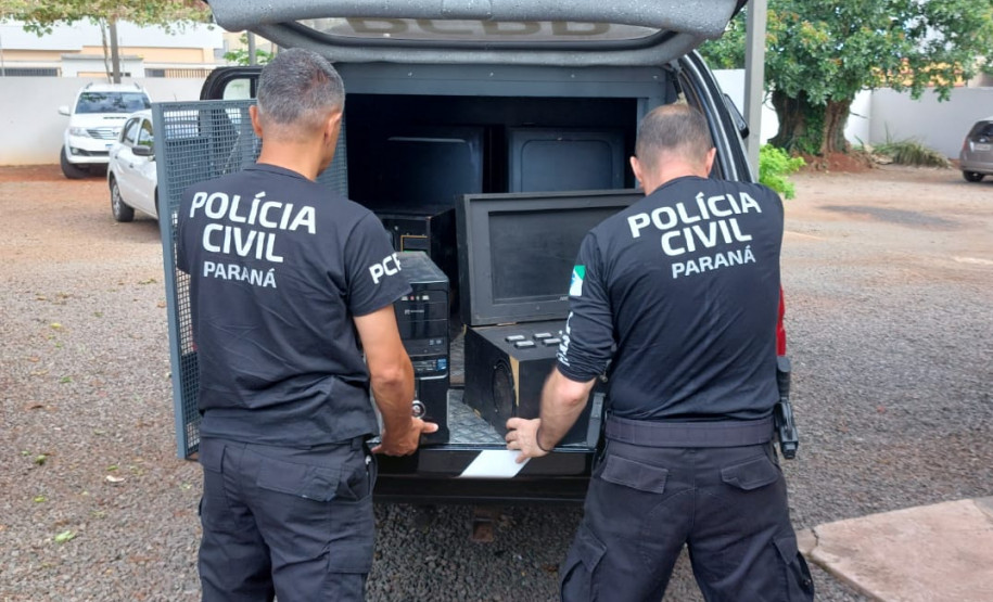 Dois policiais civis com materiais apreendidos na viatura