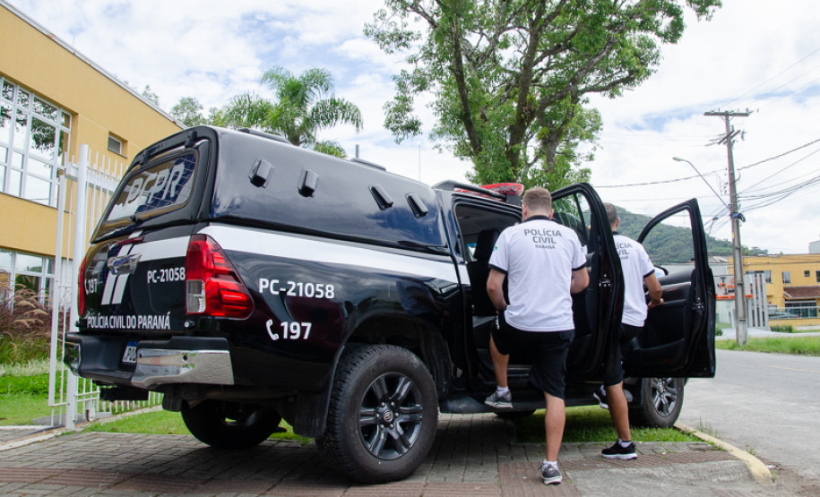 Dois policiais civis entrando em viatura
