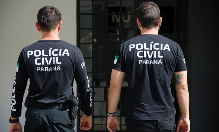 Dois policiais de costas entrando em delegacia