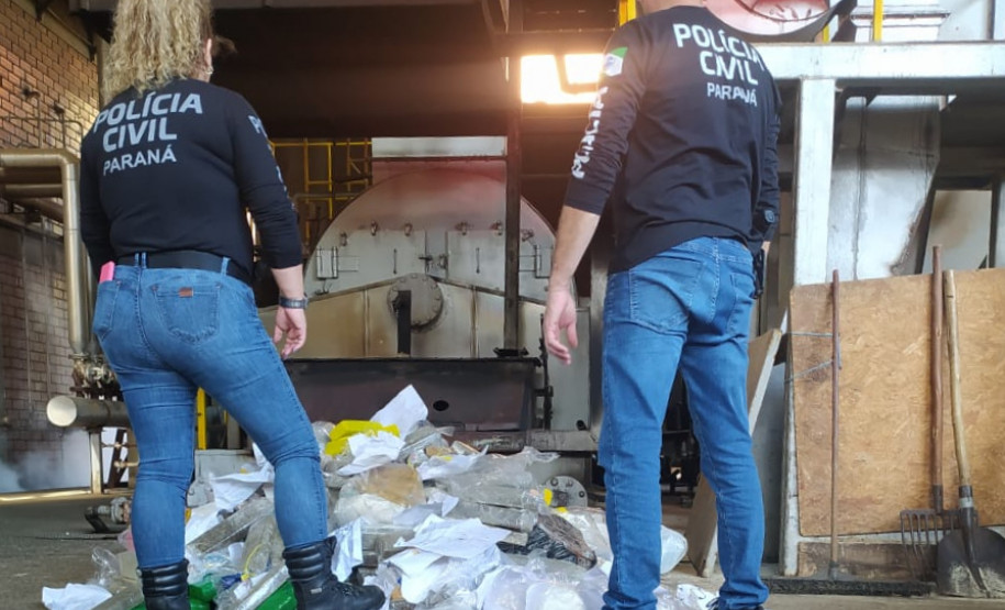 Dois policiais civis observam embalagens com drogas