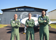Pilotos posando para fotografia em frente a um avião