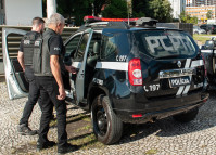 Dois policiais civis entrando em viatura